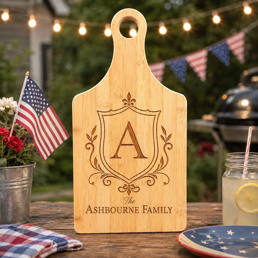 Personalized bamboo cutting board with engraved Ashbourne Family crest, shown on a patriotic 4th of July outdoor table -- lxi-context:4th-of-july